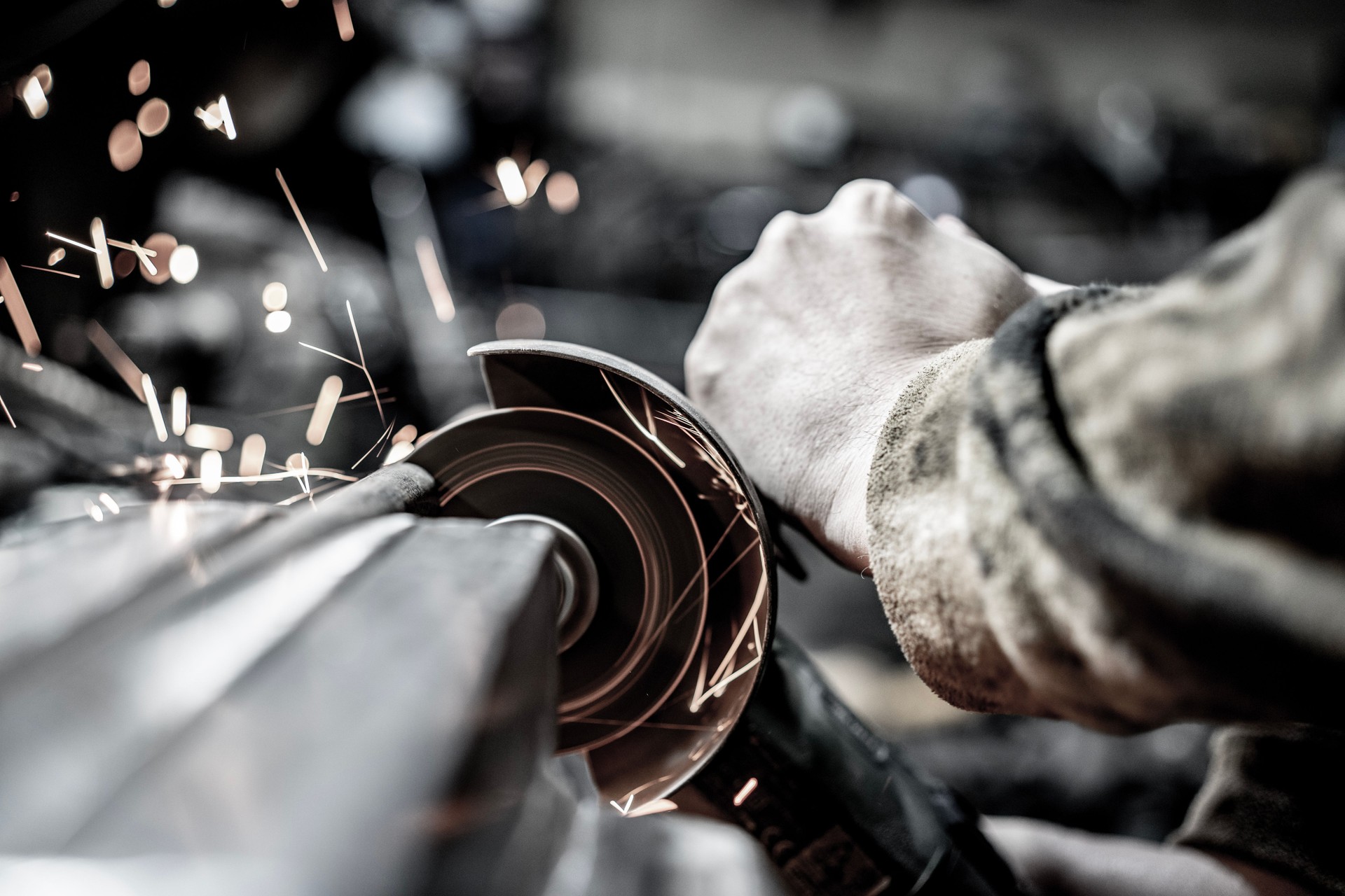 Worker Using Tools to Shape Metal with Sparks Flying in Workshop